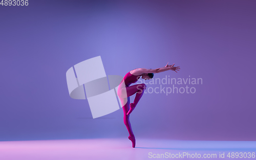 Image of Young and graceful ballet dancer isolated on purple studio background in neon light