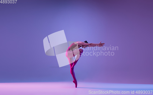 Image of Young and graceful ballet dancer isolated on purple studio background in neon light