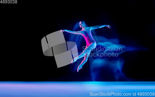 Image of Young and graceful ballet dancer isolated on black studio background in neon mixed light