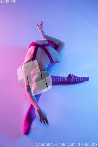 Image of Young and graceful ballet dancer isolated on purple studio background in neon light