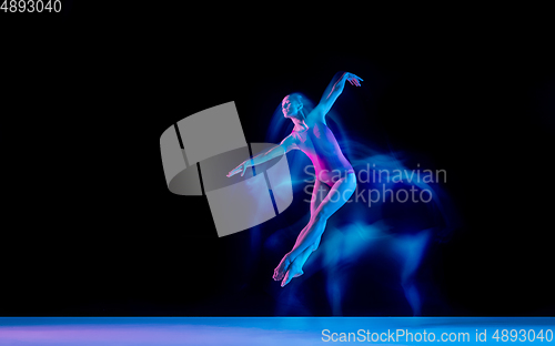 Image of Young and graceful ballet dancer isolated on black studio background in neon mixed light