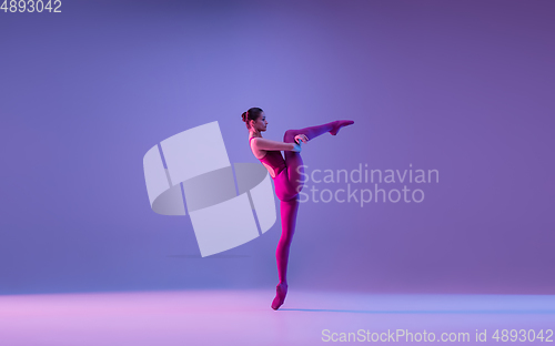 Image of Young and graceful ballet dancer isolated on purple studio background in neon light