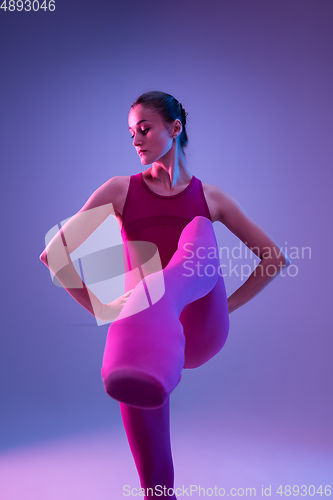 Image of Young and graceful ballet dancer isolated on purple studio background in neon light