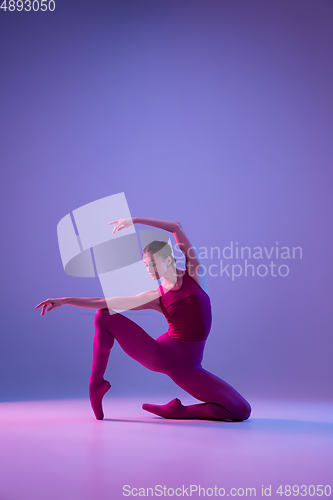 Image of Young and graceful ballet dancer isolated on purple studio background in neon light