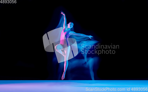 Image of Young and graceful ballet dancer isolated on black studio background in neon mixed light