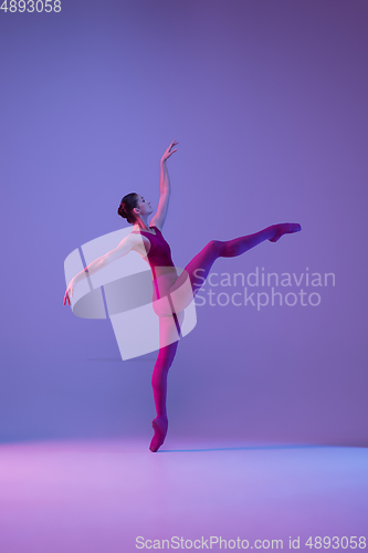 Image of Young and graceful ballet dancer isolated on purple studio background in neon light