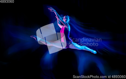 Image of Young and graceful ballet dancer isolated on black studio background in neon mixed light