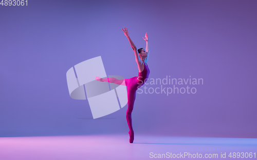 Image of Young and graceful ballet dancer isolated on purple studio background in neon light