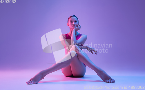 Image of Young and graceful ballet dancer isolated on purple studio background in neon light