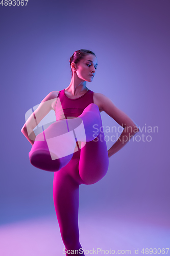 Image of Young and graceful ballet dancer isolated on purple studio background in neon light