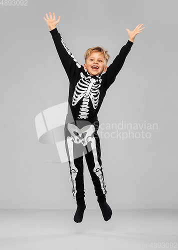 Image of happy boy in halloween costume of skeleton jumping