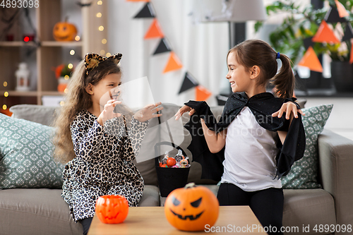 Image of girls in halloween costumes with candies at home