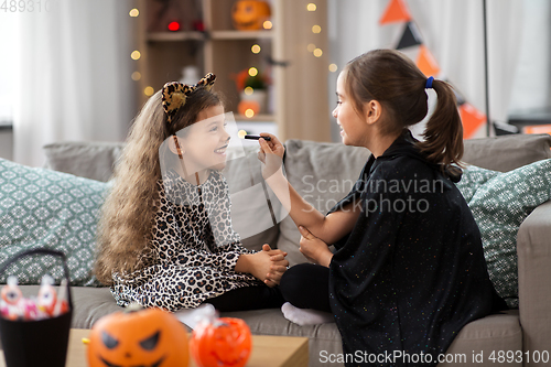 Image of girls doing face painting on halloween at home