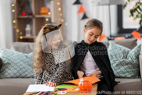 Image of girls in halloween costumes doing crafts at home