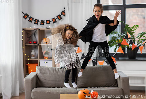 Image of girls in halloween costumes jumping on sofa