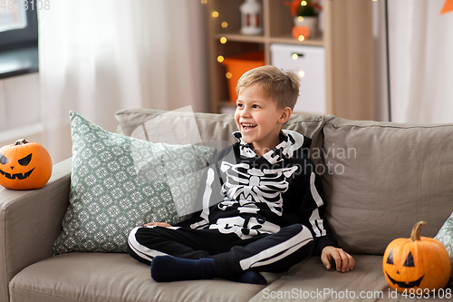 Image of happy boy in halloween costume of skeleton at home