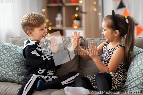 Image of kids in halloween costumes playing game at home