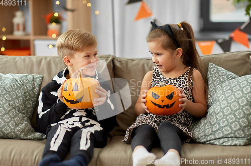 Image of kids in halloween costumes with pumpkins at home