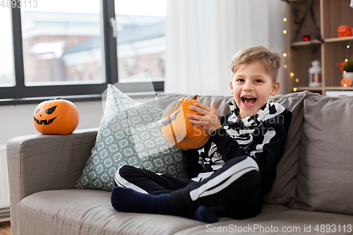 Image of boy in halloween costume with pumpkin at home