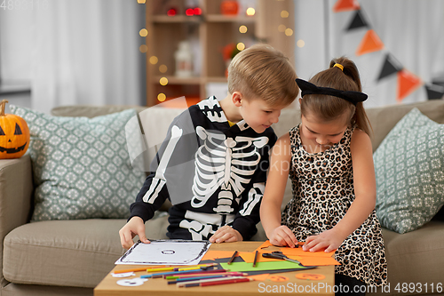 Image of kids in halloween costumes doing crafts at home