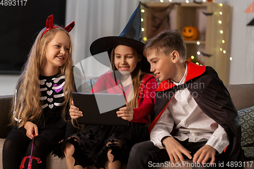 Image of kids in halloween costumes with tablet pc at home