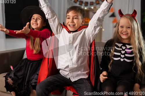 Image of kids in halloween costumes s having fun at home