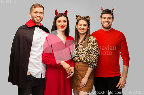 Image of happy friends in halloween costumes over grey