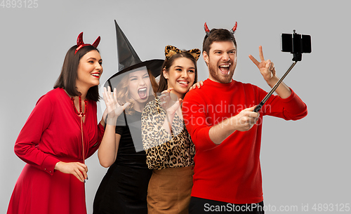 Image of happy friends in halloween costumes taking selfie