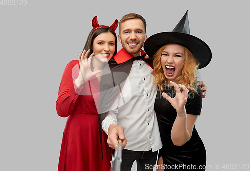 Image of happy friends in halloween costumes taking selfie