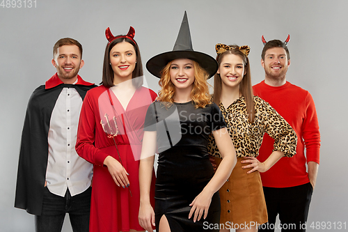 Image of happy friends in halloween costumes over grey