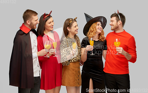 Image of happy friends in halloween costumes over grey