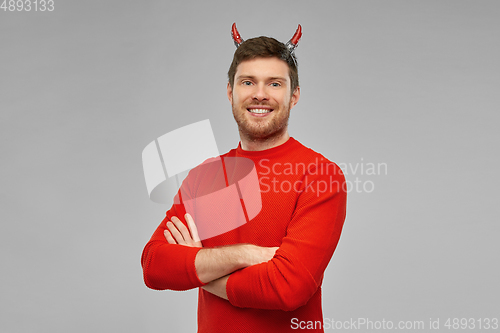 Image of happy man in halloween costume of devil over grey