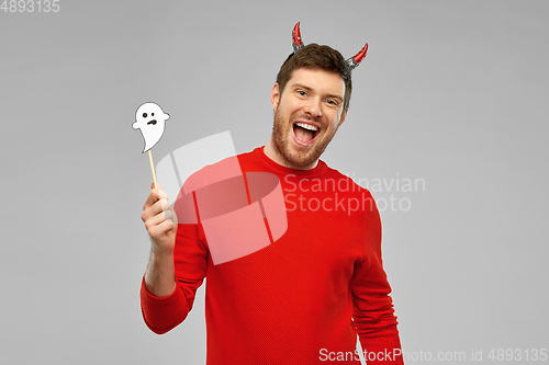 Image of happy man in halloween costume of devil over grey