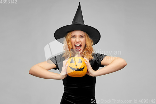 Image of woman in halloween costume of witch with pumpkin
