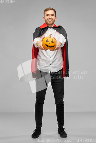 Image of man in halloween costume of vampire with pumpkin