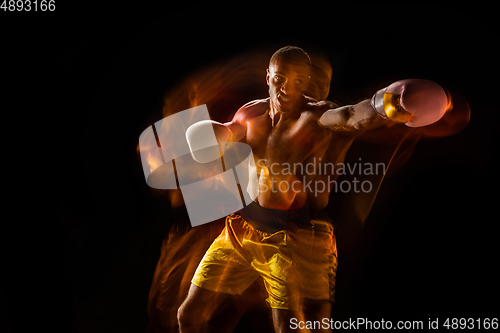 Image of Professional boxer training isolated on black studio background in mixed light