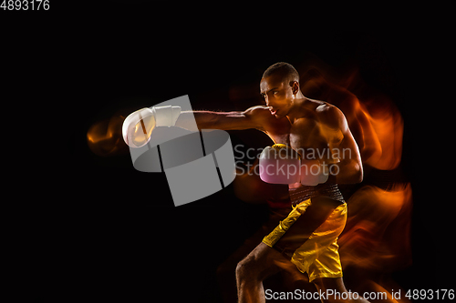 Image of Professional boxer training isolated on black studio background in mixed light