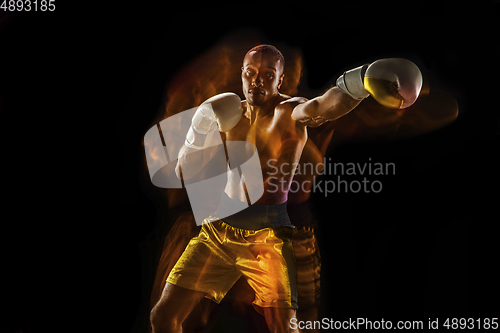 Image of Professional boxer training isolated on black studio background in mixed light