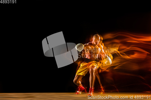 Image of Professional boxer training isolated on black studio background in mixed light