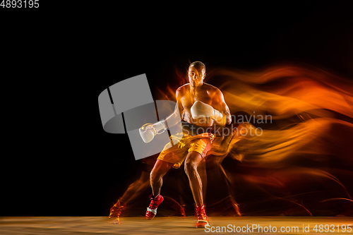 Image of Professional boxer training isolated on black studio background in mixed light