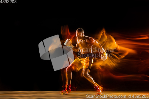 Image of Professional boxer training isolated on black studio background in mixed light