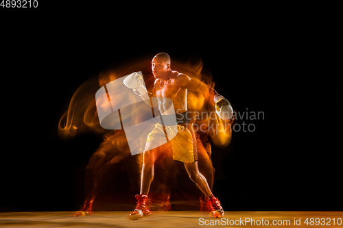 Image of Professional boxer training isolated on black studio background in mixed light