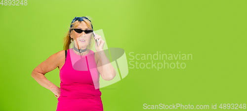 Image of Senior woman in ultra trendy attire isolated on bright green background