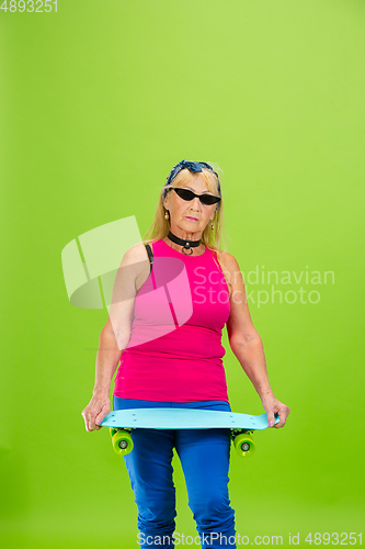 Image of Senior woman in ultra trendy attire isolated on bright green background