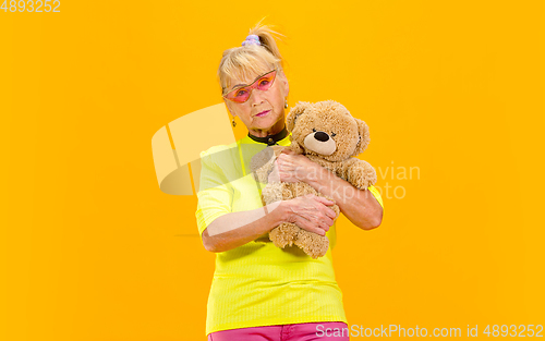 Image of Senior woman in ultra trendy attire isolated on bright orange background