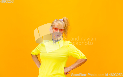 Image of Senior woman in ultra trendy attire isolated on bright orange background