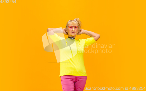 Image of Senior woman in ultra trendy attire isolated on bright orange background