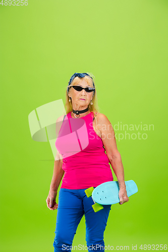 Image of Senior woman in ultra trendy attire isolated on bright green background