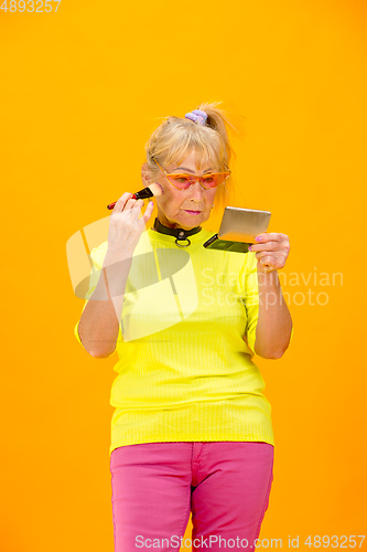 Image of Senior woman in ultra trendy attire isolated on bright orange background