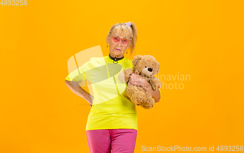 Image of Senior woman in ultra trendy attire isolated on bright orange background